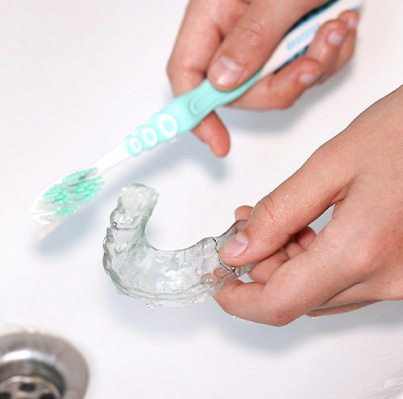 Brushing Invisalign aligner in the sink