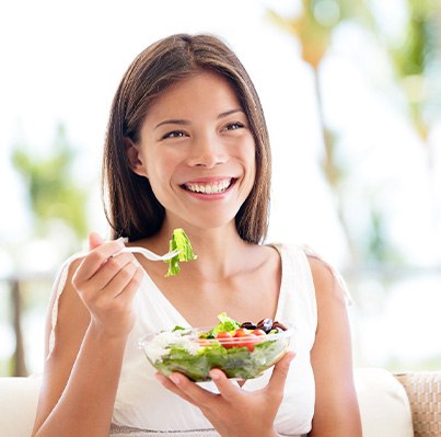 Woman sitting on couch eating a salad