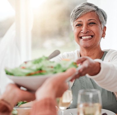 Woman smiling while grabbing bowl of salad