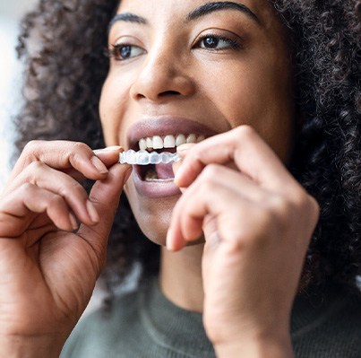 Woman with curly hair putting in Invisalign aligner