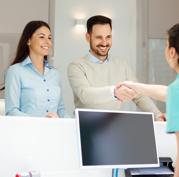 Dentistry team member greeting two dental patients