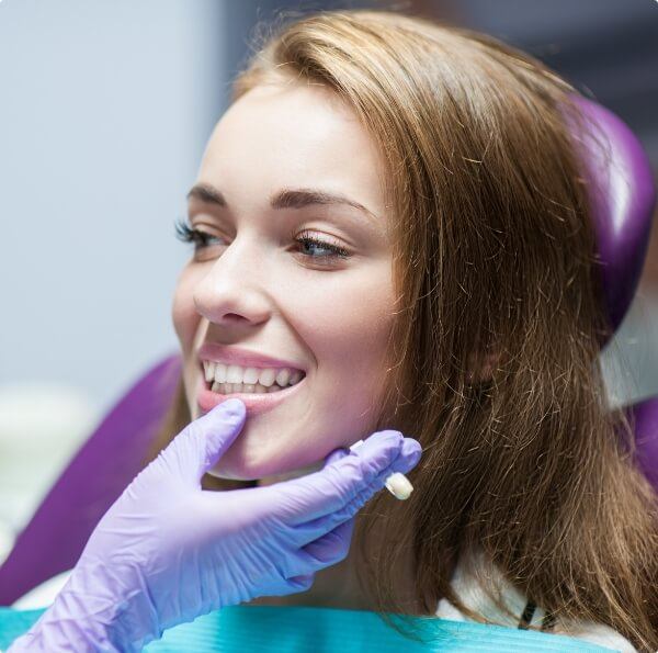 Dentist examining woman's smile after dental crown supported fixed bridge treatment