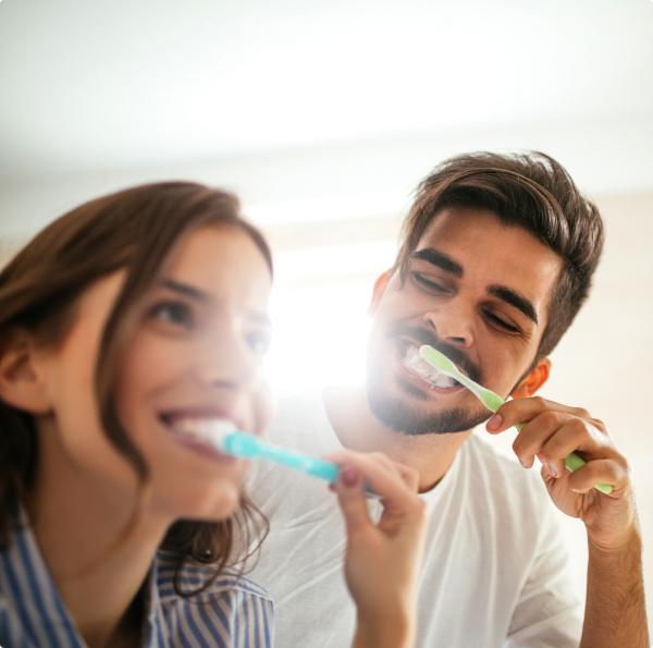 Man and woman brushing teeth to prevent dental emergencies