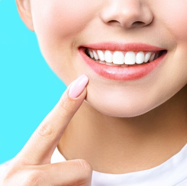 Woman pointing to bright smile after teeth whitening