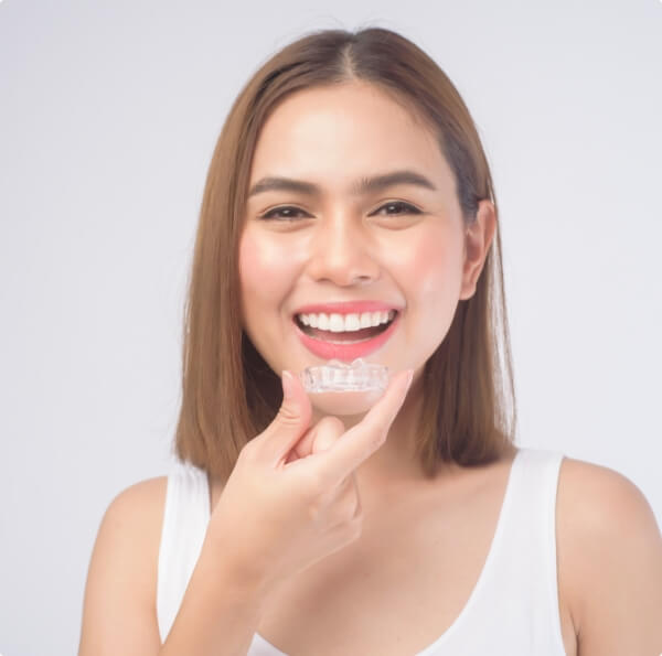 Smiling woman holding an Invisalign tray