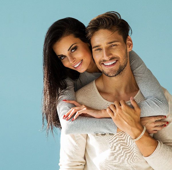 a couple grinning after undergoing a smile makeover 