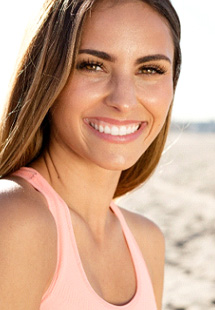 Woman in orange tank top at beach smiling