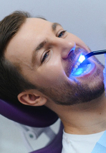 Dentist applying UV light to man’s tooth-colored filling