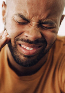 Man in pain pressing hand to sore jaw with eyes cinched shut