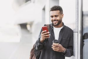 person leaning against a building and checking their phone