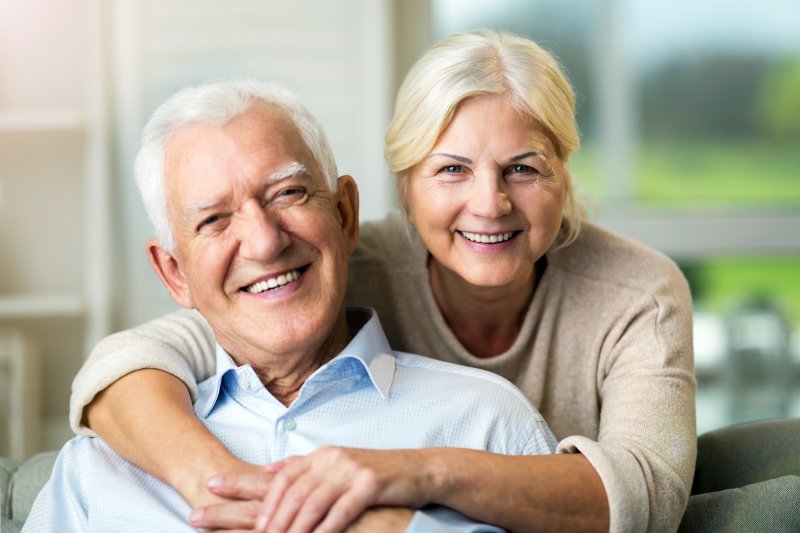 an older couple hugging and smiling after receiving their new dental implants