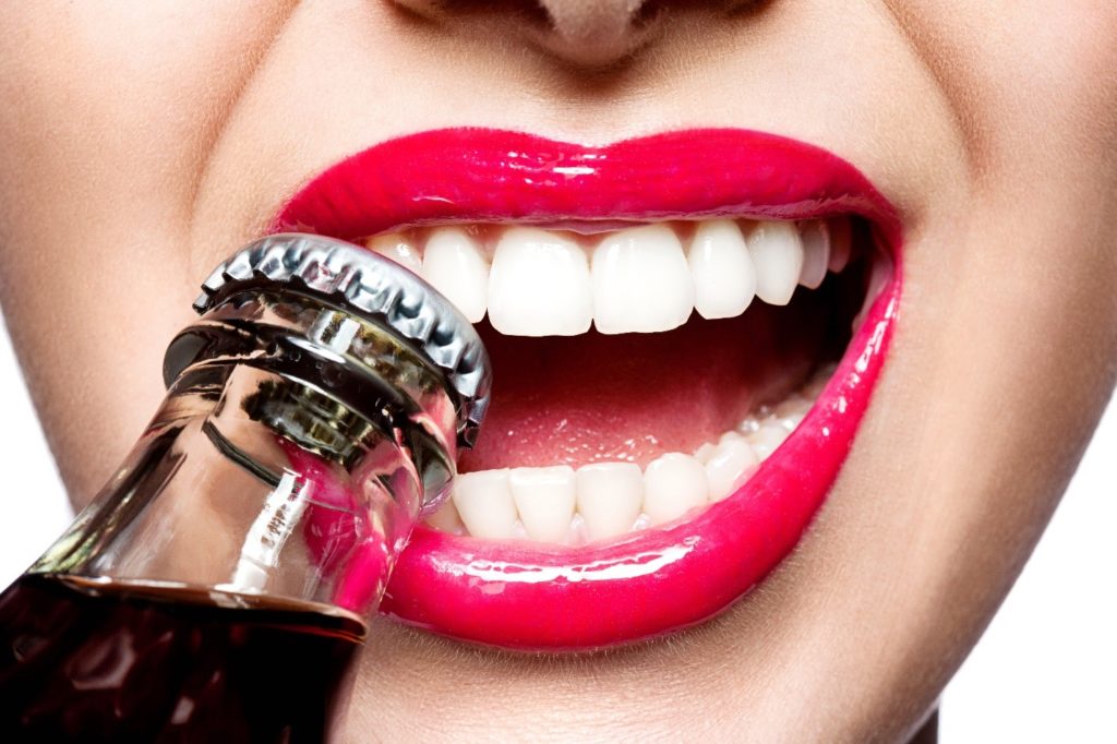 Patient with red lipstick using teeth to open bottle cap