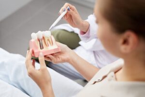 Woman holds model of dental implant while dentist explains.