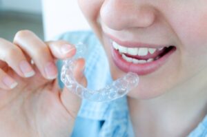 Clear aligner going into person's mouth.