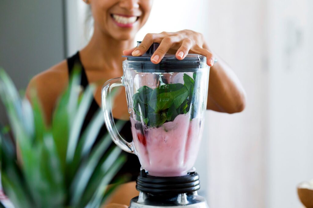 Woman pureeing spinach and strawberries in blender