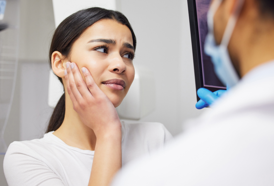 Woman at dentist holding jaw in pain
