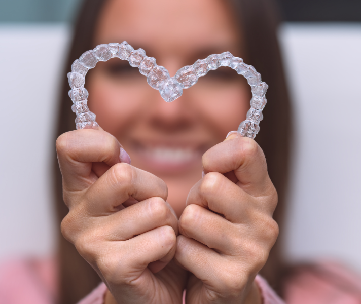Woman holding clear aligners in heart shape